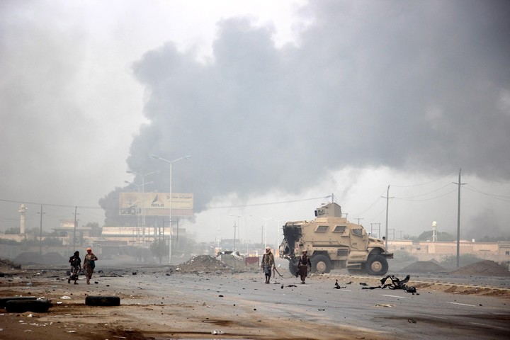 Ataques.  Miembros de las fuerzas del gobierno yemení patrullan mientras ascienden por las columnas de humor de una supuesta posición hutí (EFE)