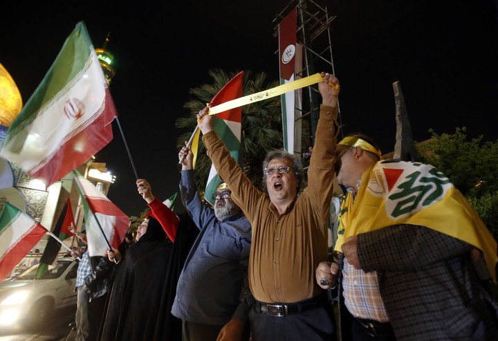 La gente sostiene banderas iraníes y palestinas durante una manifestación contra Israel después de que Irán lanzara ataques con drones contra Israel en la Plaza Palestina de Teherán.  Foto EFE/EPA/Abedin Taherkenareh.
