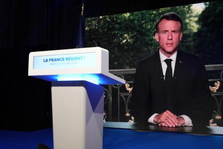 El presidente francés, Emmanuel Macron, aparece en la pantalla de televisión en la sede de la noche electoral del partido de extrema derecha francés Agrupación Nacional, el domingo 9 de junio de 2024 en París.  El presidente francés Emanuel Macron disuelve la Asamblea Nacional y convoca nuevas elecciones legislativas tras la derrota en la votación de la UE (Foto AP/Lewis Joly)