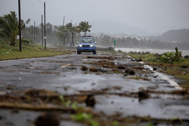 Un auto avanza por un camino cubierto de ramas y restos dejados por la tormenta en Puerto Rico. Foto: Reuters