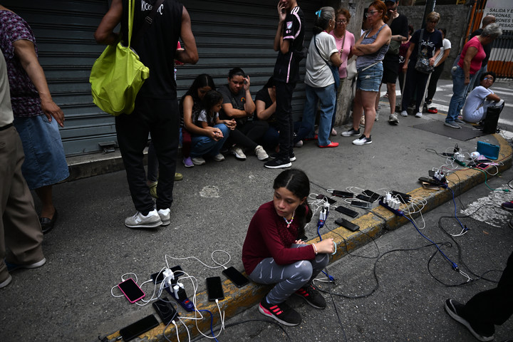 Cargando mi teléfono en un lugar donde rara vez tenía electricidad en Caracas. AFP 