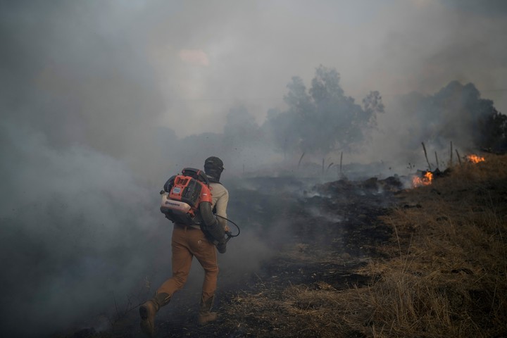 Un guardabosques trabajó para apagar un incendio mientras un grupo desesperado del Líbano llegaba a un campo abierto en el norte de Israel. FotoAP