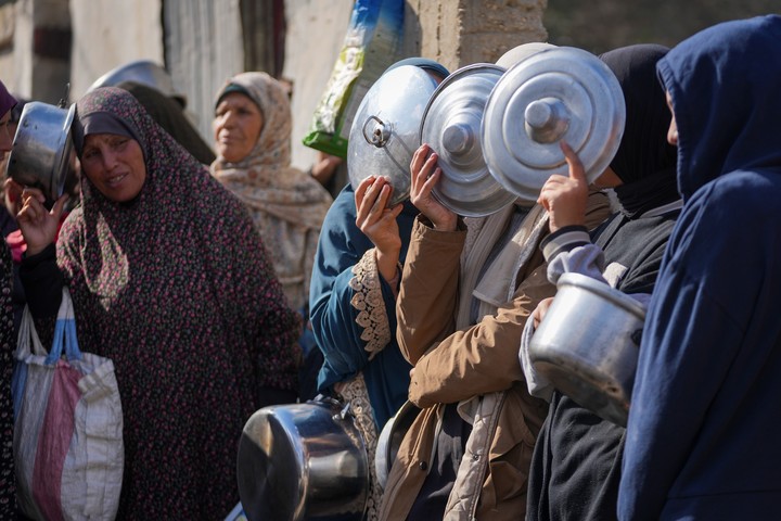 Las mujeres se cubren el pico mientras hacen cola para conseguir comida. Foto: AP 