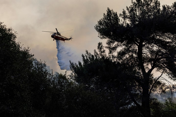 Un helicóptero arroja agua sobre un incendio forestal. Foto: AP 